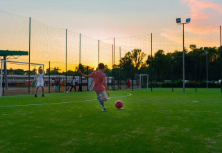 Kinderen voetballen bij zonsondergang op een veld in Camping Roma Capitol, een vakantiepark in Lazio, Italië.