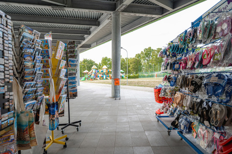 Winkel met souvenirs, ansichtkaarten en sandalen bij Camping Roma Capitol in Lazio, Italië, met speeltuin buiten.