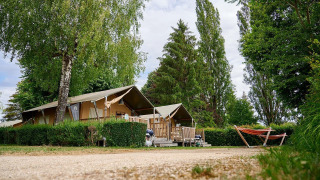 Safaritent Villatent Wood bij Camping Le Coin Tranquille in Frankrijk, met bomen en een hangmat.