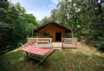 Außenansicht des Villatent Wood Safari-Zeltes mit Veranda und Hängematte auf Camping Le Pech Charmant, Frankreich.