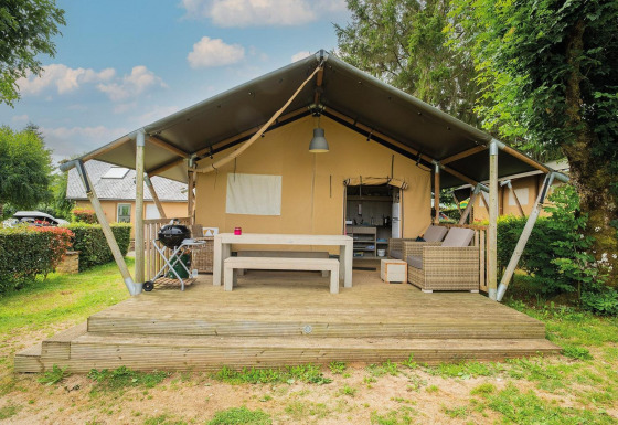 Safaritent Villatent Nomad met houten terras en buitenzitje op Camping Les Genêts in Frankrijk.