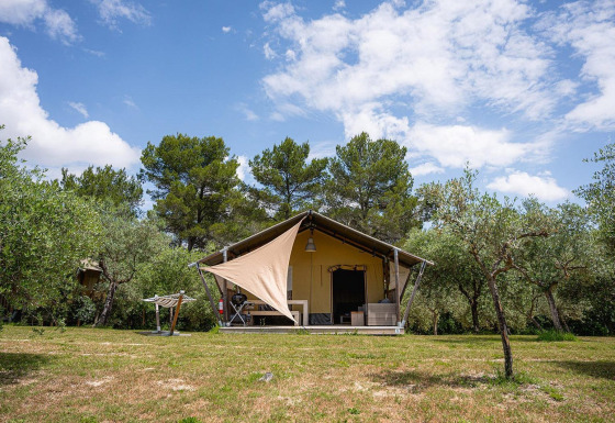 Tienda safari Villatent Nomad en Camping Pian Di Boccio, Italia, rodeada de árboles y cielo azul.