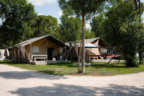 Tiendas safari Villatent Nomad en Camping Punta Navaccia, Italia, rodeadas de árboles y zonas de relax.