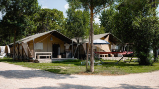 Safari-Zelte Villatent Nomad auf dem Campingplatz Punta Navaccia in Italien, umgeben von Bäumen und Grünflächen.