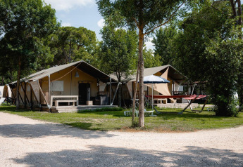 Tiendas safari Villatent Nomad en Camping Punta Navaccia, Italia, rodeadas de árboles y zonas de relax.