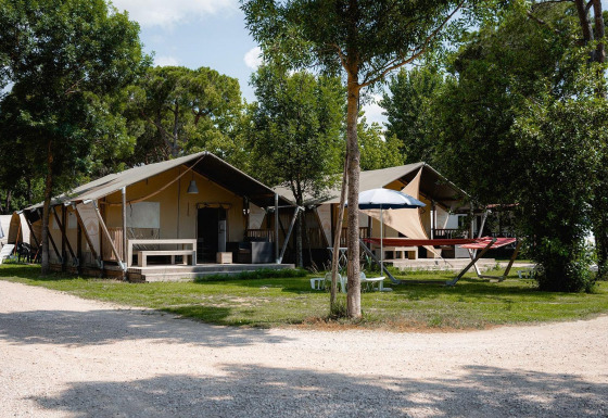 Tiendas safari Villatent Nomad en Camping Punta Navaccia, Italia, rodeadas de árboles y zonas de relax.