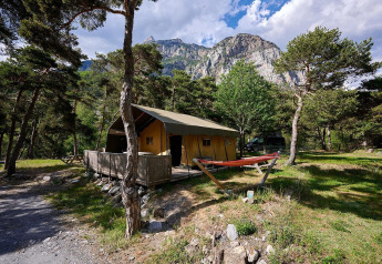 Safari-Zelt Villatent Wood auf Camping River in Frankreich, umgeben von Bäumen und Bergen.