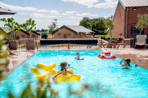 Bambini che giocano in piscina a FarmCamps Hoeve Luyterheyde, parco vacanze in Brabante Settentrionale, Paesi Bassi.