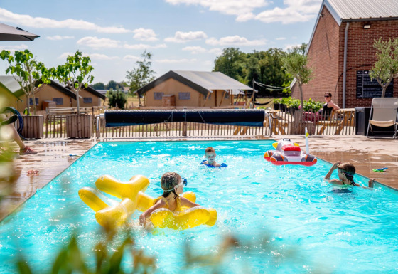 Børn leger i swimmingpoolen på FarmCamps Hoeve Luyterheyde, en feriepark i Nord-Brabant, Holland.