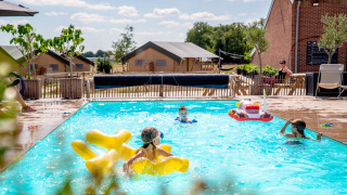 Børn leger i swimmingpoolen på FarmCamps Hoeve Luyterheyde, en feriepark i Nord-Brabant, Holland.