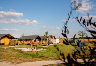 Lejrhytter og legeplads på FarmCamps Hoeve Luyterheyde i Nordbrabant, Holland, på en solrig dag.