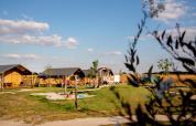 Lejrhytter og legeplads på FarmCamps Hoeve Luyterheyde i Nordbrabant, Holland, på en solrig dag.