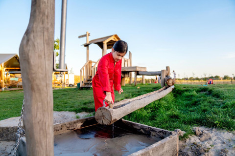 Bambino gioca con canale d'acqua in legno a FarmCamps Hoeve Luyterheyde nel Brabante Settentrionale, Olanda.