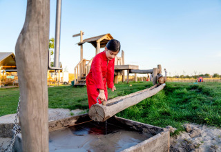 Bambino gioca con canale d'acqua in legno a FarmCamps Hoeve Luyterheyde nel Brabante Settentrionale, Olanda.