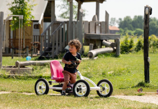 Un bambino guida un go-kart a pedali sull’erba vicino all’area giochi di FarmCamps Hoeve Luyterheyde, Olanda.