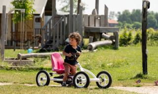 A child rides a pedal go-kart on the grass near the playground at FarmCamps Hoeve Luyterheyde in Holland.