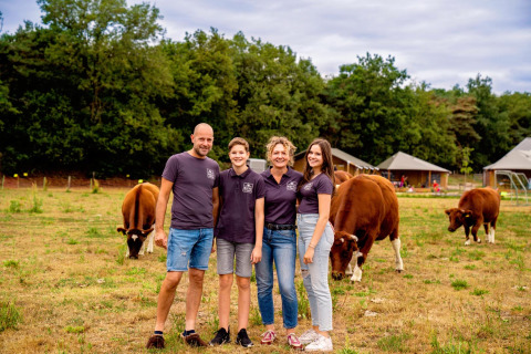 Familia en FarmCamps Hoeve Luyterheyde en Brabante Septentrional, Países Bajos, con vacas y casas de vacaciones detrás.