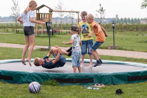 Children are playing on a large trampoline at FarmCamps Op Flakkee holiday park in South-Holland, Netherlands.