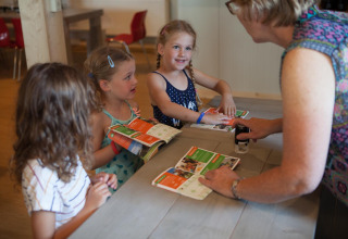 Kinderen krijgen een stempel in hun activiteitenboekjes van een volwassene bij FarmCamps Op Flakkee, Zuid-Holland.