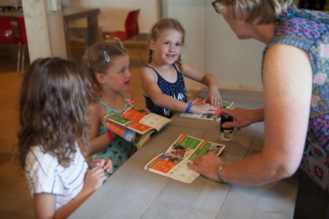 Niños reciben sellos en sus cuadernos de actividades de un adulto en FarmCamps Op Flakkee, Holanda Meridional.