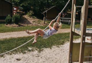 Bambina che si diverte su una corda nel parco giochi di Camping het Horstmannsbos, Drenthe, Paesi Bassi.