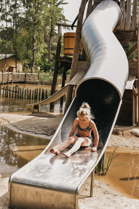 Een kind glijdt van een metalen glijbaan op Camping het Horstmannsbos, een vakantiepark in Drenthe, Nederland.