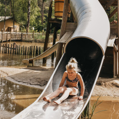 Ein Kind rutscht auf einer Metallrutsche im Camping het Horstmannsbos, einem Ferienpark in Drenthe, Niederlande.