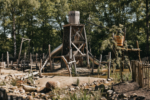 Wooden playground area with a tower and slide at Camping het Horstmannsbos holiday park, Drenthe, Netherlands.