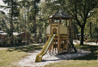 Parco giochi con casetta di legno e scivolo al Camping het Horstmannsbos, villaggio vacanze a Drenthe, Paesi Bassi.