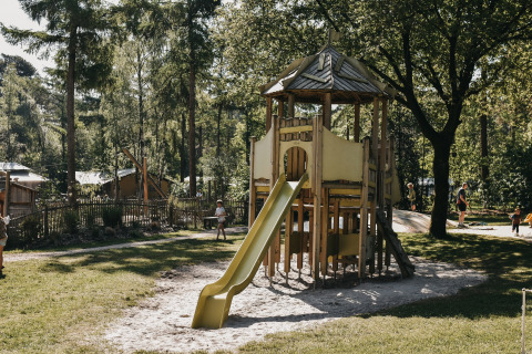 Spielplatz mit Holzspielhaus und Rutsche im Camping het Horstmannsbos, Ferienpark in Drenthe, Niederlande.