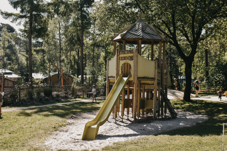 Spielplatz mit Holzspielhaus und Rutsche im Camping het Horstmannsbos, Ferienpark in Drenthe, Niederlande.
