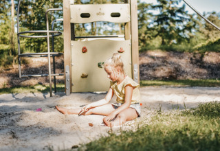 Una bambina gioca nella sabbiera nel parco giochi di Camping het Horstmannsbos, villaggio vacanze in Drenthe.