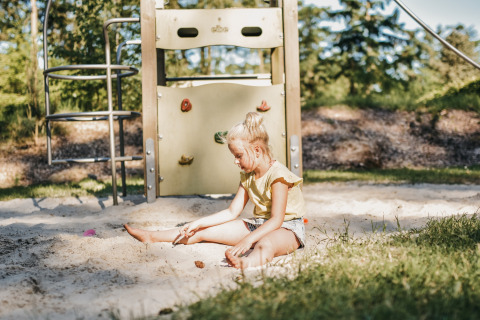 Ein Mädchen spielt im Sandkasten auf dem Spielplatz im Ferienpark Camping het Horstmannsbos in Drenthe.