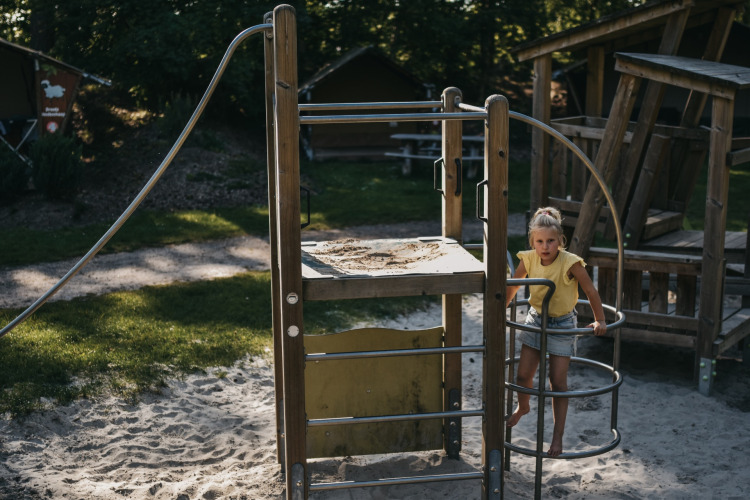 Ein Kind spielt auf einem Holzspielplatz mit Sand im Camping het Horstmannsbos, Drenthe, Niederlande.