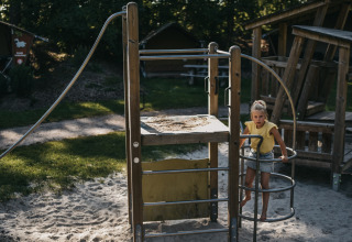 Un bambino gioca su un parco giochi di sabbia con strutture di legno a Camping het Horstmannsbos, Drenthe, Paesi Bassi.