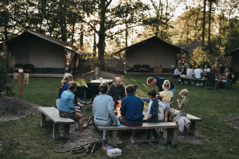 Familien sitzen am Lagerfeuer auf Camping het Horstmannsbos, einem Ferienpark in Drenthe, Niederlande.