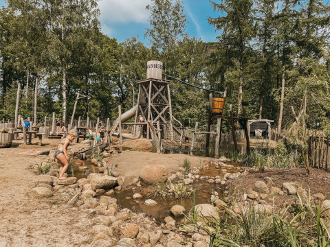 Des enfants jouent dans un espace de jeux d'eau au Camping het Horstmannsbos, entouré d'arbres à Drenthe.