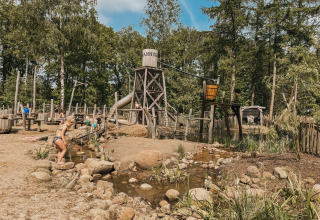Des enfants jouent dans un espace de jeux d'eau au Camping het Horstmannsbos, entouré d'arbres à Drenthe.