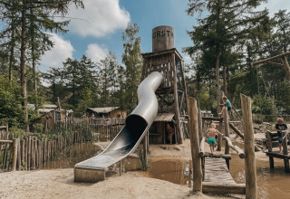 Kinder spielen auf einem Abenteuerspielplatz mit Rutsche und Hängebrücke in Camping het Horstmannsbos, Drenthe.