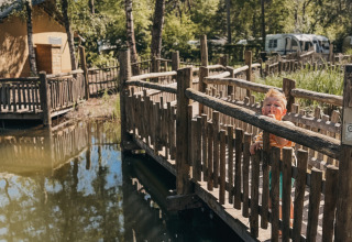 Bambino su un ponte di legno sopra l’acqua al Camping het Horstmannsbos, Drenthe, Paesi Bassi.