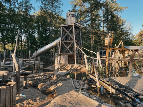 Spielplatz mit Holzturm, Rutsche und Wasserbereich im Camping het Horstmannsbos, Drenthe, Niederlande.