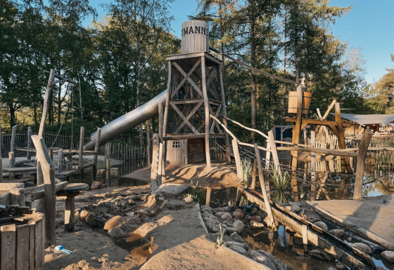 Area giochi con torre di legno, scivolo e acqua al Camping het Horstmannsbos, Drenthe, Paesi Bassi.