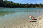 Kinderen spelen aan het zandstrand van het meer bij Camping het Horstmannsbos in Drenthe, omgeven door bomen.
