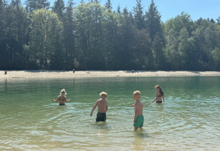 Children wading in the lake at Camping het Horstmannsbos, a holiday park surrounded by forest in Drenthe.