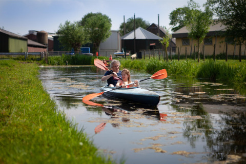 Zwei Personen paddeln im Kajak auf einem Kanal bei FarmCamps Stolkse Weide in Südholland.