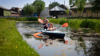 Twee mensen kajakken op een sloot bij FarmCamps Stolkse Weide, een vakantiepark in Zuid-Holland.
