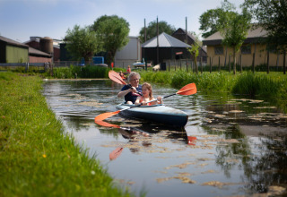 Twee mensen kajakken op een sloot bij FarmCamps Stolkse Weide, een vakantiepark in Zuid-Holland.
