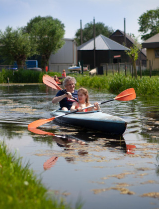 Dos personas en kayak por un canal en FarmCamps Stolkse Weide, un parque vacacional en Holanda del Sur.