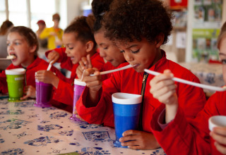 Des enfants en rouge dégustent des boissons à la paille à FarmCamps Stolkse Weide, aux Pays-Bas.