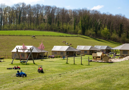 Foto van FarmCamps De Verloren Kost in Limburg, Nederland met safaritenten, speeltuin en groene weiden.
